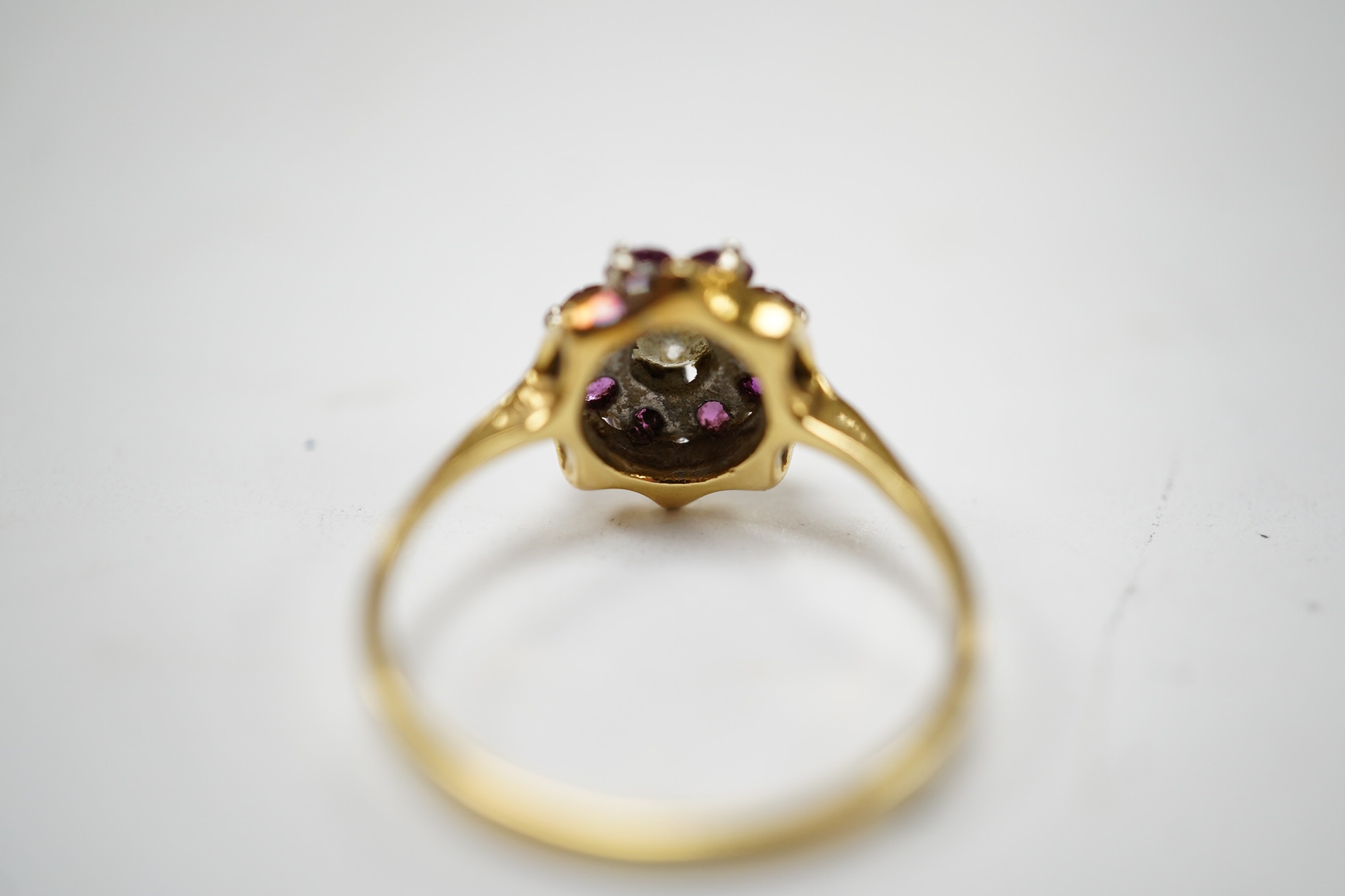 An 18ct, ruby and diamond set circular cluster ring, size O, gross weight 3 grams. Condition - fair